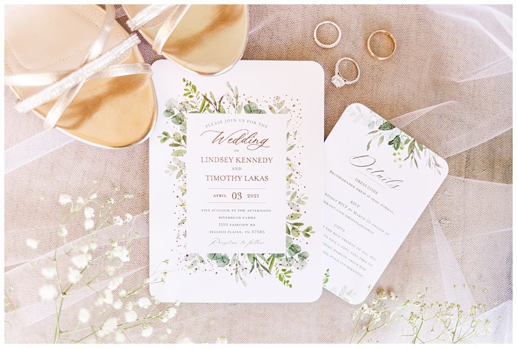 photo-friendly wedding timeline - detail photo of a wedding invitation suite with white, gold, and greenery, rings, and shoes