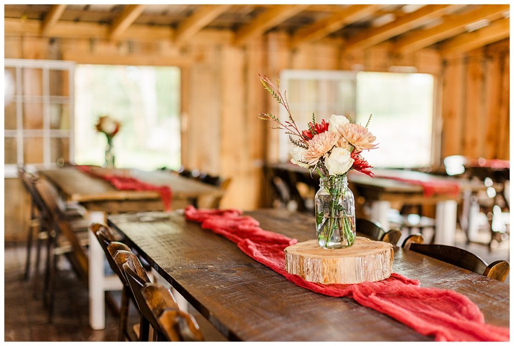 reception details, barn reception with orange, white, and red floral centerpieces in mason jars